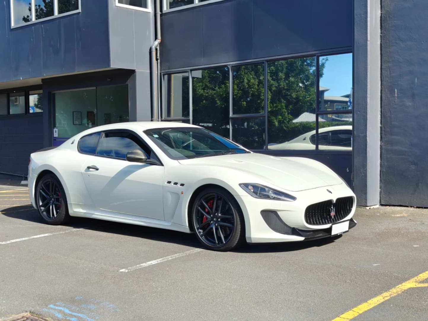 2011 Maserati GranTurismo MC Stradale in white parked outside performance garage with aggressive front grille and carbon accents